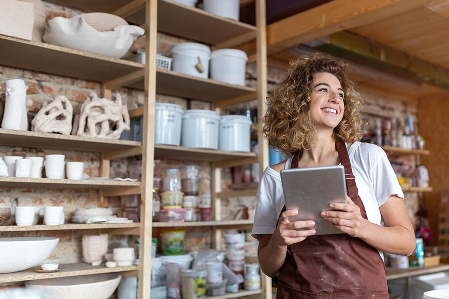 Woman stands proudly inside her pottery business.