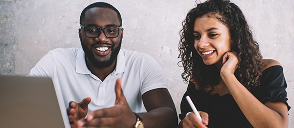 male and female smiling at a laptop